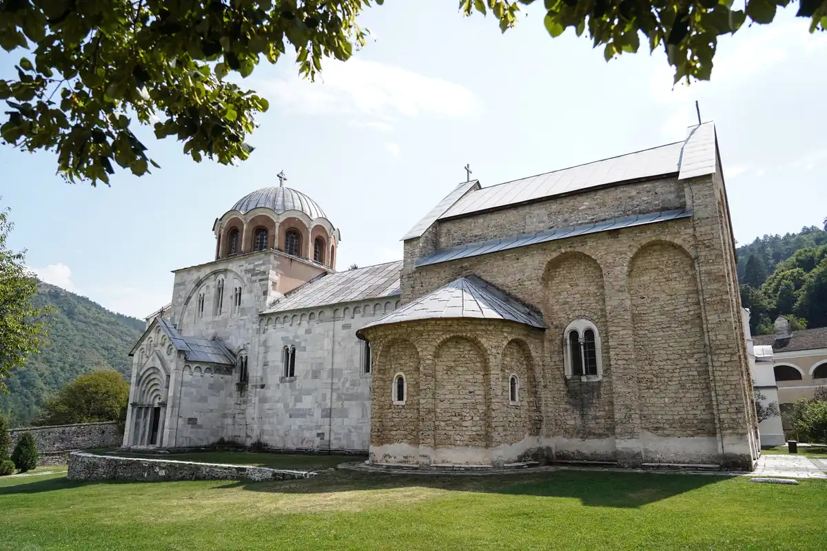 Bogorodičina crkva manastira Studenica od belog mermera, sa kupolom na visokom tamburu, na travnjaku pod drvećem, okružena brdima