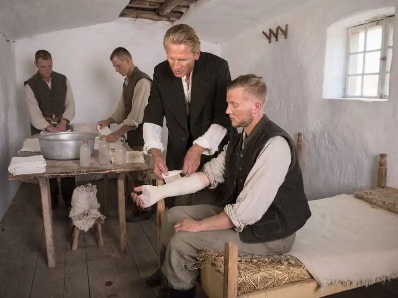 Lekar previja vojnika u improvizovanom previjalištu, rekonstrukcija 1876.
