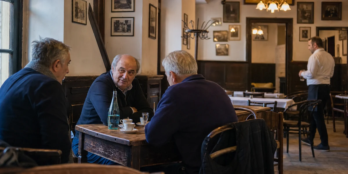 Prijatelji razgovaraju za drvenim stolom u staroj gradskoj kafani